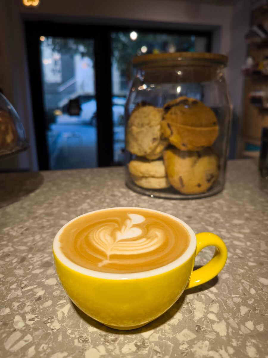 Cappuccino în ceașcă galbenă lângă borcanul cu cookies