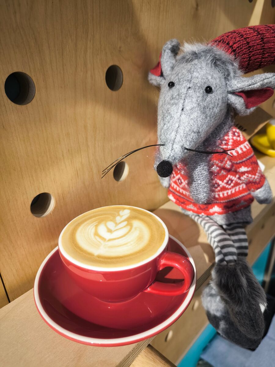 Cappuccino în ceașcă roșie, lângă șoricelul de pe raft