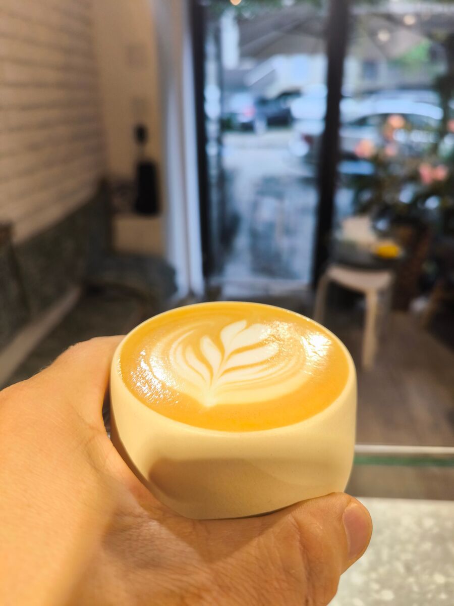 Cappuccino cu rozetă în ceașca albă a casei